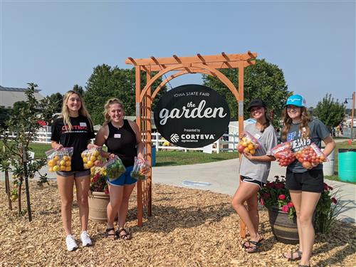 Students holding produce grown at the Iowa State Fair garden